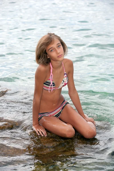 Dospívající dívka sedící na skále v moři — Stock fotografie