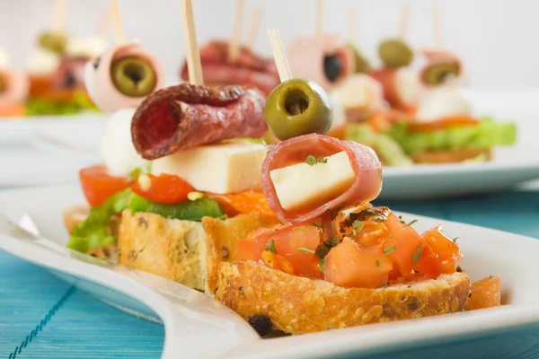 Bruschetta with prosciutto, olive, cheese and tomato — Stock Photo, Image