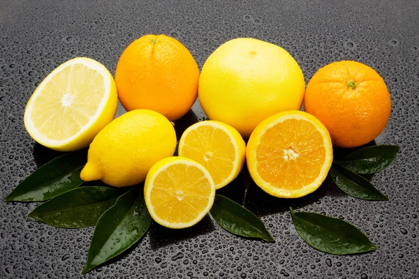 Portakal, limon ve greyfurt ıslak surgace üzerinde — Stok fotoğraf