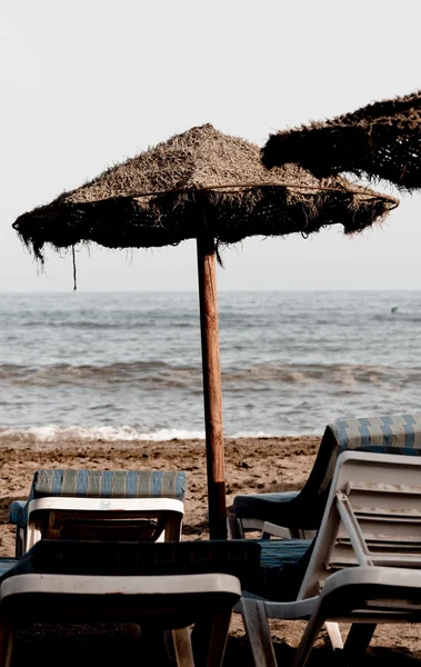 Соломенный зонтик и стулья — стоковое фото