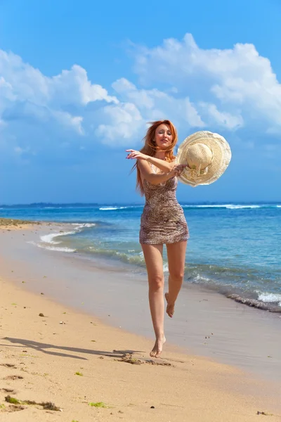 Молодая изящная женщина выходит на берег океана со шляпой в руках — стоковое фото