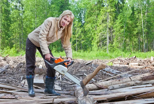 Die junge Frau in Holz sägt einen Baum mit einer Kettensäge — Stockfoto