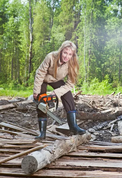 A jovem mulher em serras de madeira uma árvore uma serra de corrente — Fotografia de Stock