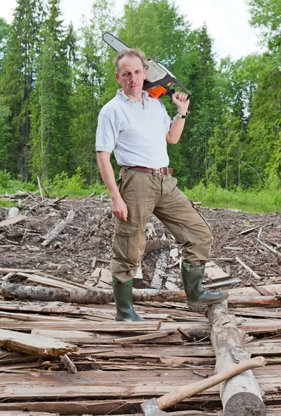 O homem em serras de madeira uma árvore uma serra de corrente — Fotografia de Stock