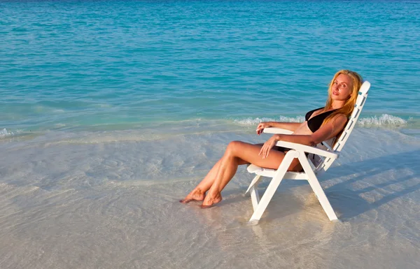 Молода красива жінка пил у пляжному кріслі, вона покладена в океан — стокове фото