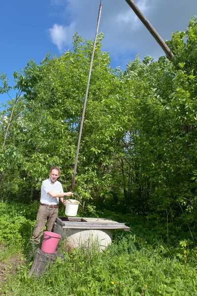 井戸の男はバケツに水を注ぎ — ストック写真