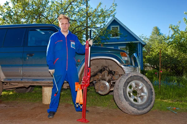 Mannen i arbetar overaller ersätter ett hjul på en off-road bil — Stockfoto