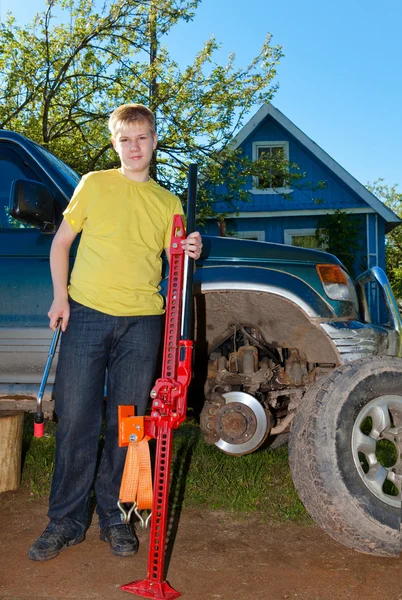 Der junge Mann, der Teenager ersetzt ein Rad an einem Geländewagen — Stockfoto