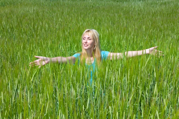Šťastná mladá žena na poli zelených uší — Stock fotografie