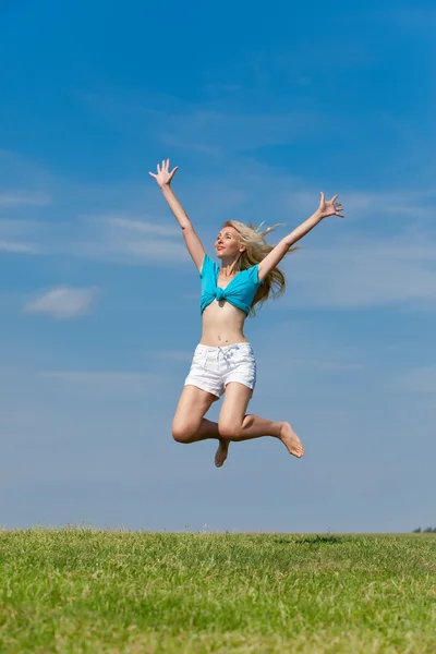 Η ευτυχισμένη νεαρή γυναίκα πηδάει στο χωράφι. — Φωτογραφία Αρχείου