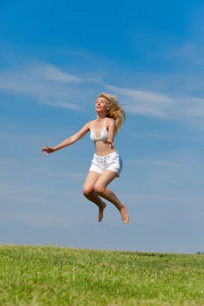 A boldog fiatal nő ugrik a mezőn — Stock Fotó