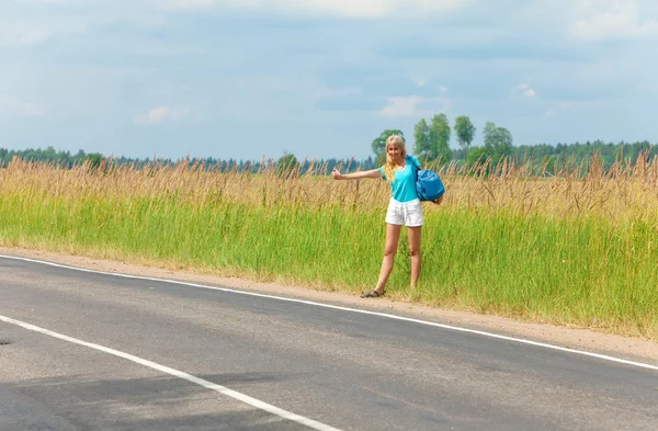 Autostopowiczka głosuje na dziewczynę na drodze — Zdjęcie stockowe