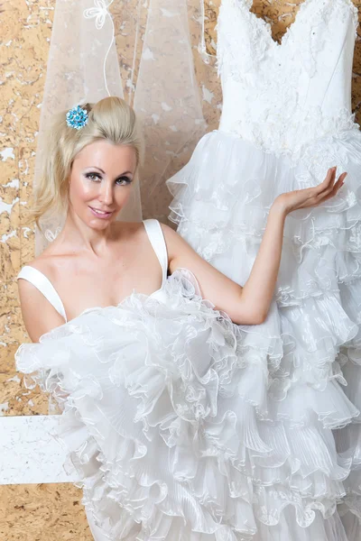 Die glückliche Braut probiert ein Hochzeitskleid an — Stockfoto