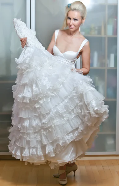 La novia feliz se prueba un vestido de novia — Foto de Stock