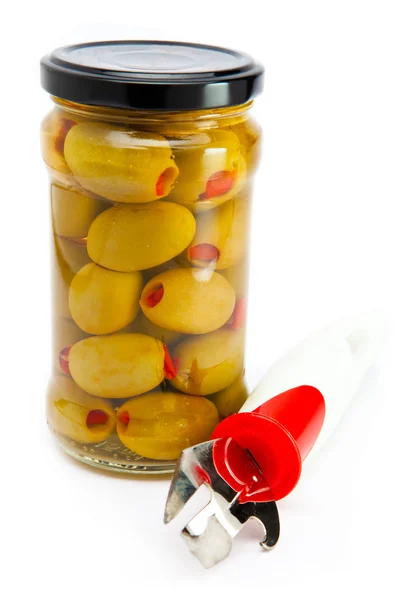 Glasburk med konserverade oliver och en konservöppnare — Stockfoto