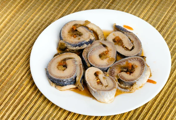 stock image Rolls from a herring on a plate, on a straw support