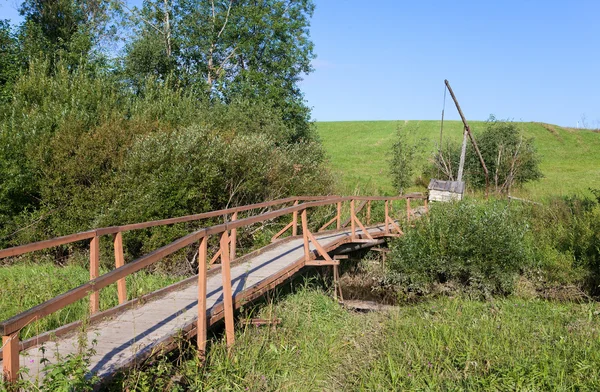 Деревянный мост через ручей к колодцу — стоковое фото
