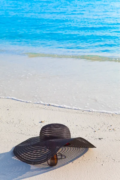 Napszemüveg és kalap feküdt a homokba tenger szélén — Stock Fotó