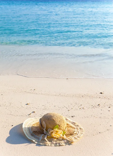 Il cappello di paglia rimane su sabbia a orlo di mare — Foto Stock
