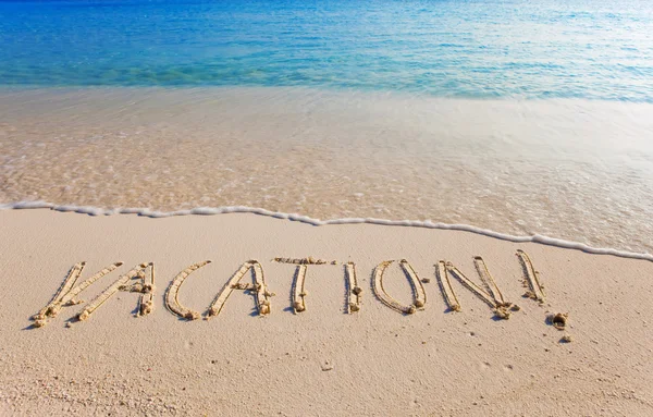 Op een strand is het geschreven "vakantie" — Stockfoto
