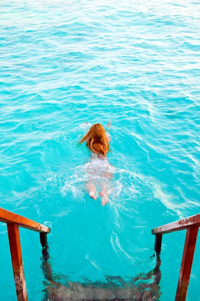 Maldives.Young sports woman swims from steps of villa on water. — Stock Photo, Image
