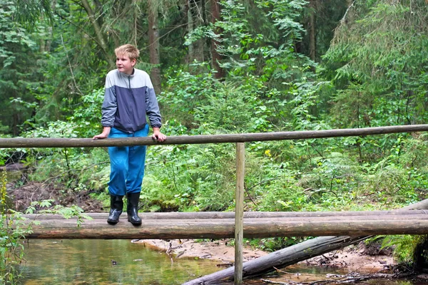 Der Junge im Holz, auf der Holzbrücke — Stockfoto