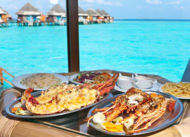 Two plates with lobster on table at window with view on ocean clipart