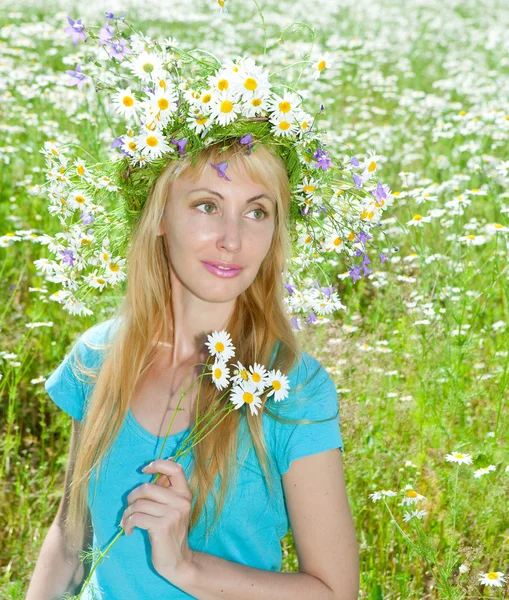 The happy young woman in a wreath from wild flowers in the field — Stock Photo, Image