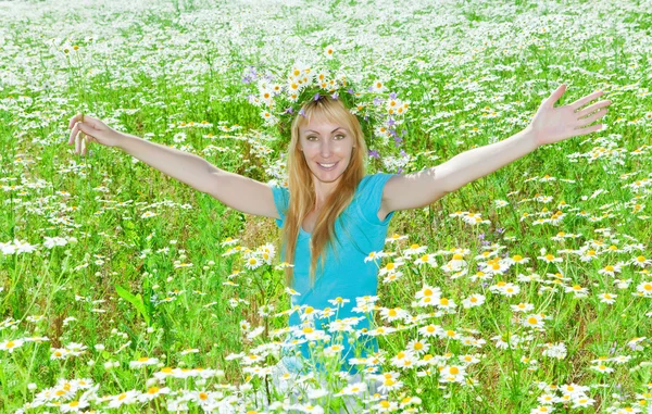 La joven feliz en una corona de flores silvestres en el campo — Foto de Stock