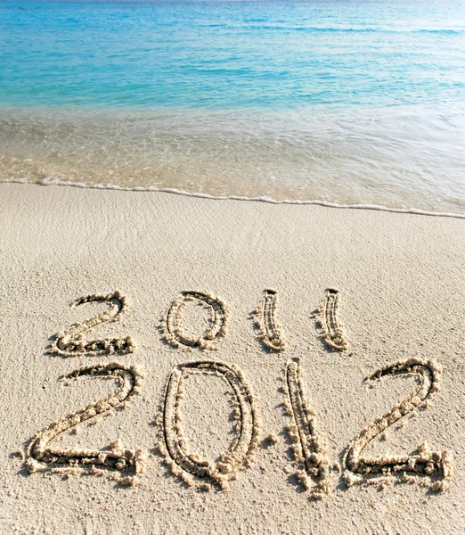 Na piasek na brzegu oceanu jest napisane "2011-2012" — Zdjęcie stockowe