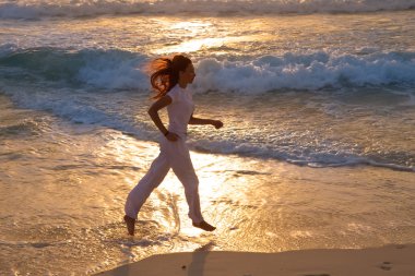 silueta de mujer, en la puesta del sol a lo largo de la costa del océano