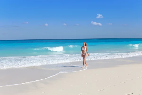 Den unga kvinnan går på en strand vid havet kanten — Stockfoto