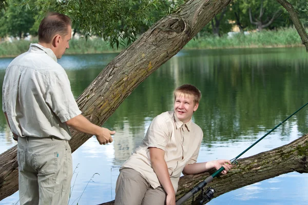 Отец тоже просит у сына рыболовного снасти для рыбалки. — стоковое фото