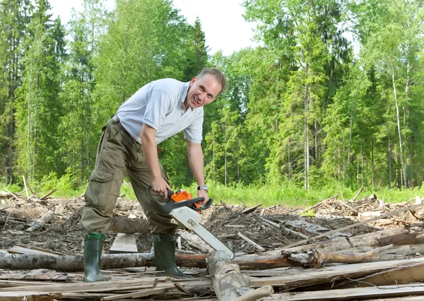 Förvånad mannen med en motorsåg i sommar trä — Stockfoto