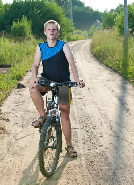 Teenager goes on bicycle on country road — Stock Photo, Image