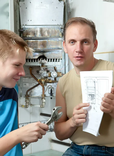The father and the son-teenager together look the instruction on repair a g — Stock Photo, Image
