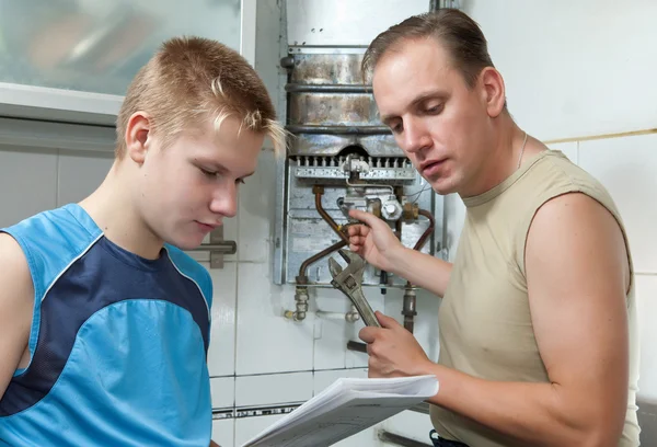 El padre y el hijo-adolescente juntos miran la instrucción en la reparación de un g — Foto de Stock