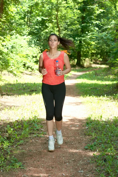 Fitness girl jogging through the woods in summer — Stock Photo, Image