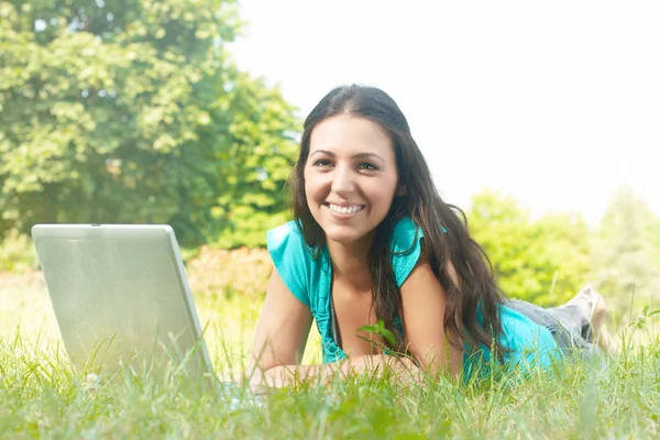 Retrato de una hermosa mujer joven usando el ordenador portátil en el parque —  Fotos de Stock