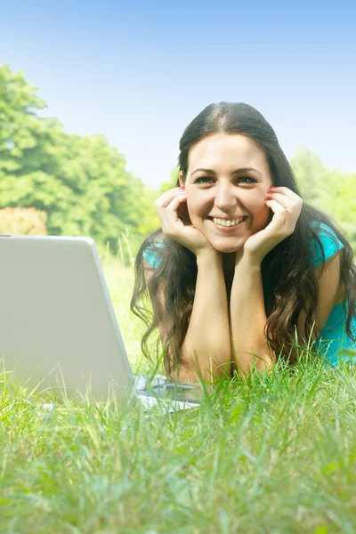 Portret van mooie jonge vrouw met laptop in het park — Stockfoto