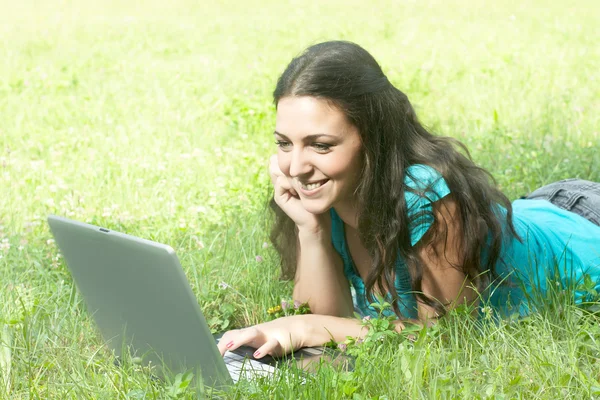 Молода жінка з ноутбуком лежить на траві — стокове фото