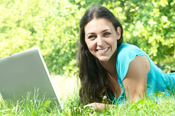 Portrait de belle jeune femme utilisant un ordinateur portable dans le parc — Photo
