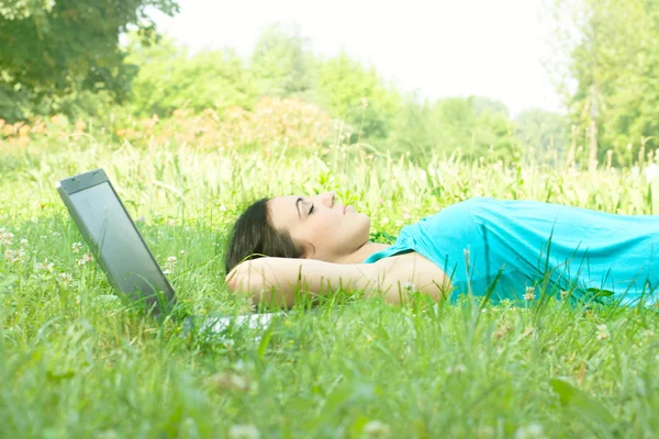 Vacker ung kvinna avkopplande på gräs med laptop — Stockfoto