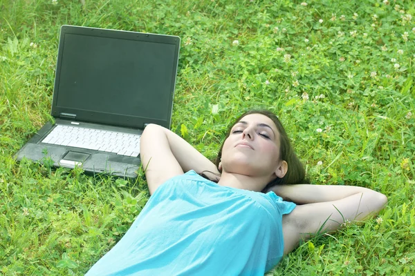 stock image Beautiful young woman relaxing on grass with laptop