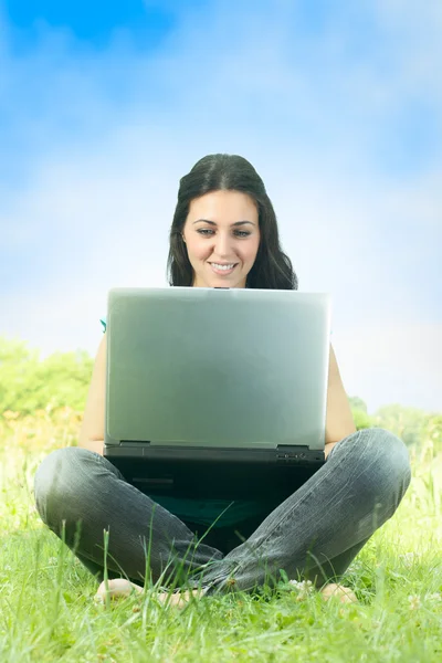 Çim bir dizüstü bilgisayar kullanarak parkta oturan şirin kız portresi — Stok fotoğraf