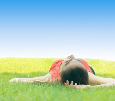 Young woman relaxing on green grass at the park clipart