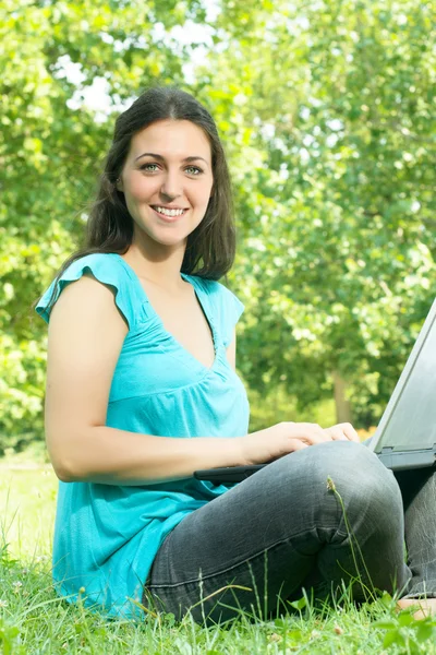 Retrato de bela jovem mulher usando laptop no parque — Fotografia de Stock