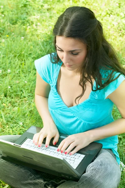 Portret ładny dziewczyna siedzi na trawie w parku przy pomocy pewien laptop — Zdjęcie stockowe