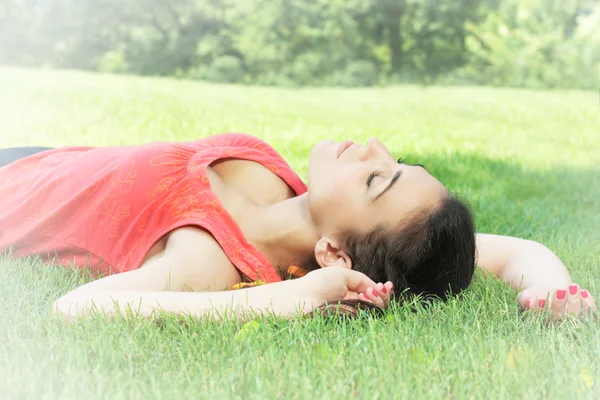 Mujer joven relajándose en la hierba verde en el parque — Foto de Stock
