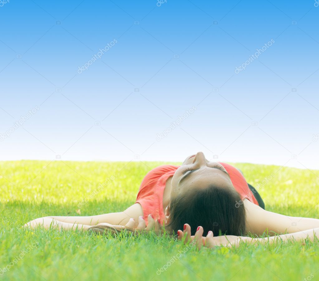 Young woman relaxing on green grass at the park
